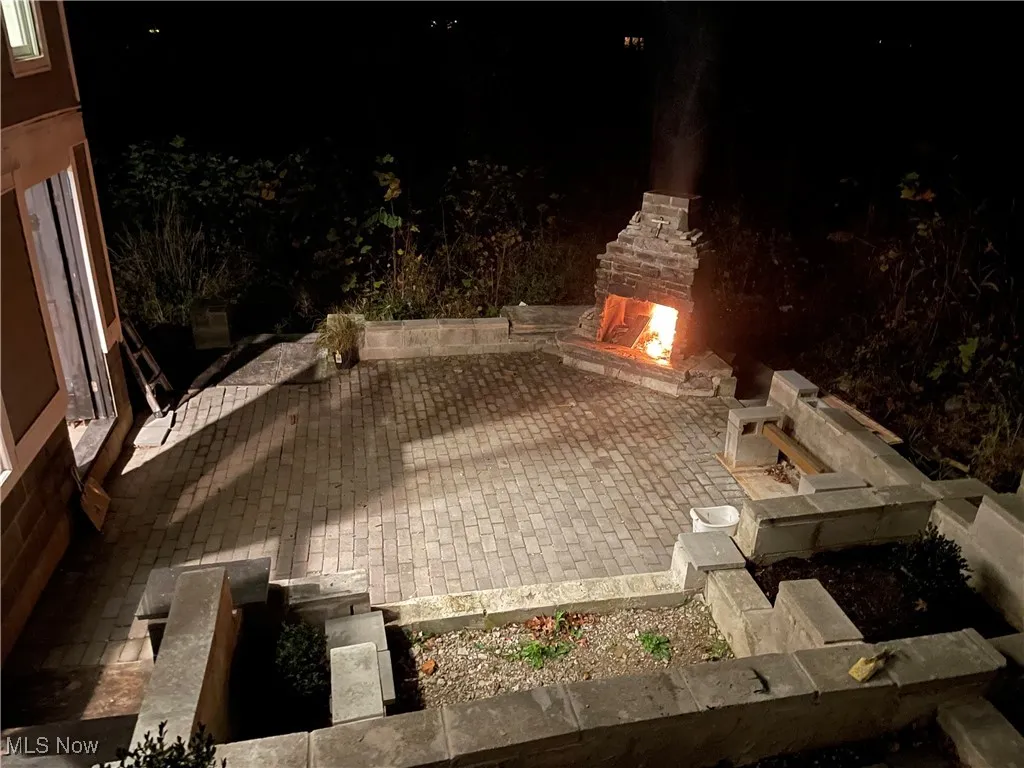 Patio at twilight featuring a lit fireplace