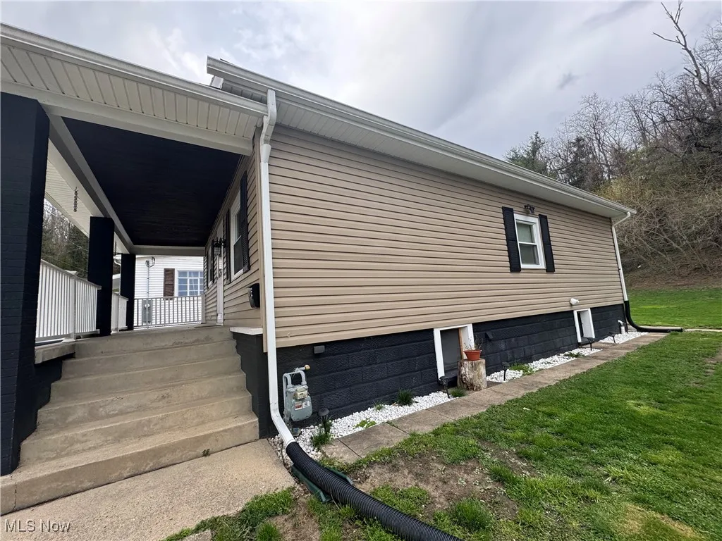 View of side of home with covered porch and a yard