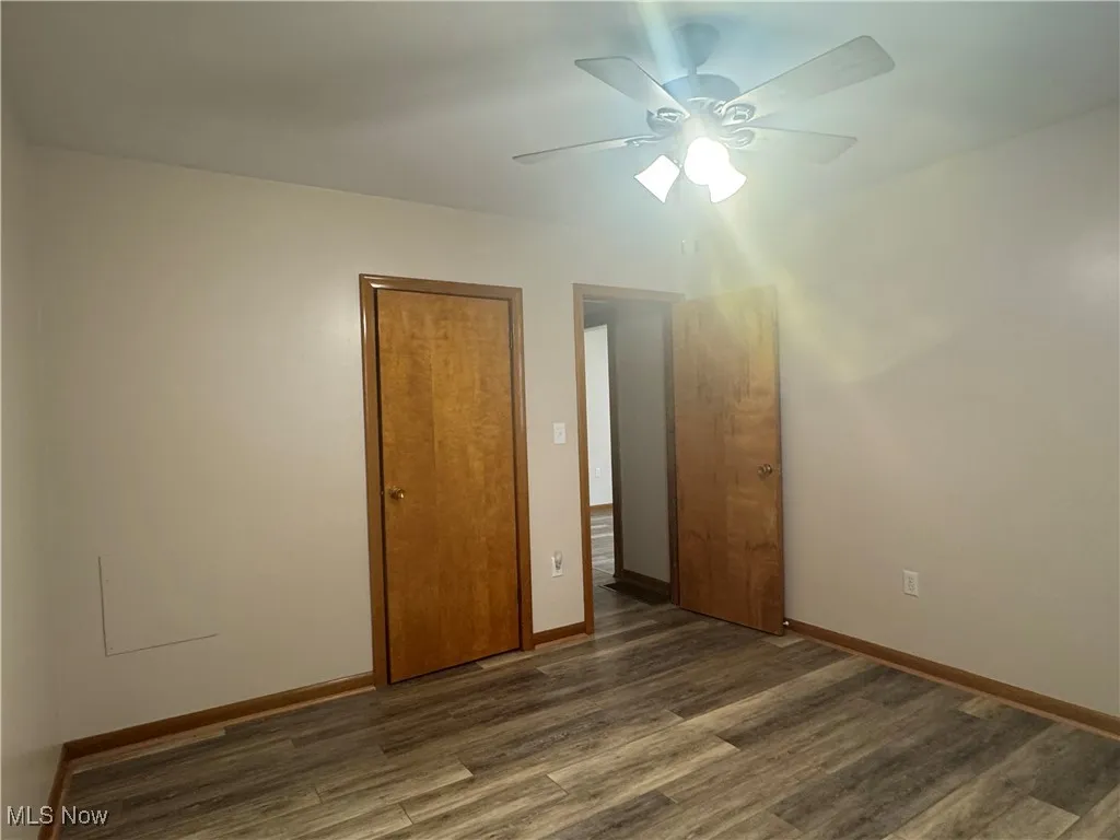 Unfurnished room with baseboards, wood finished floors, and a ceiling fan