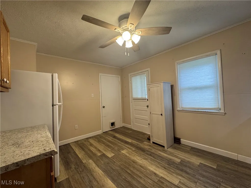 Kitchen with a textured ceiling, ornamental molding, dark wood-type flooring, and a ceiling fan