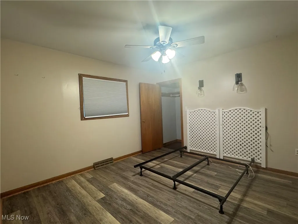 Unfurnished bedroom with a ceiling fan, wood finished floors, baseboards, and visible vents