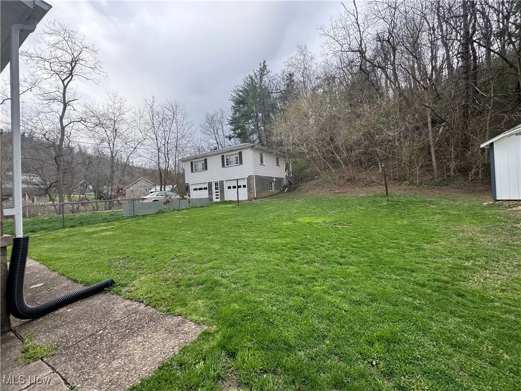 View of yard with fence, driveway, and a garage