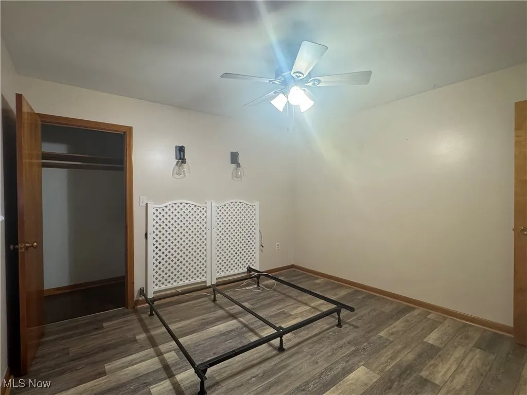 Unfurnished bedroom featuring baseboards, a closet, ceiling fan, and wood finished floors