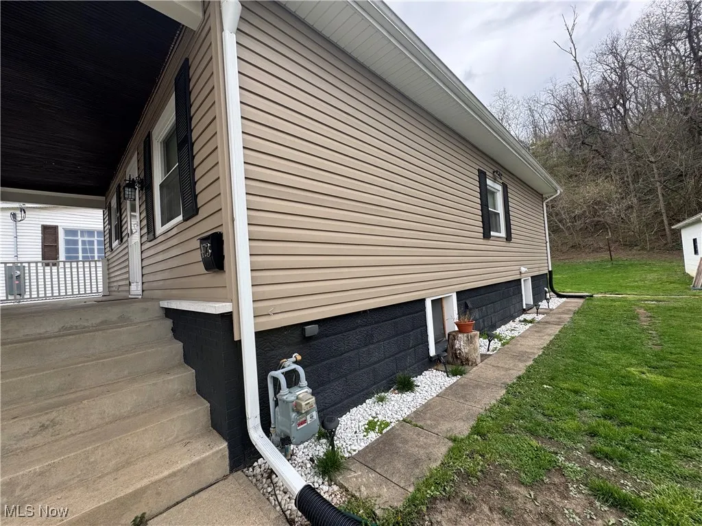 View of home's exterior with a lawn and a porch