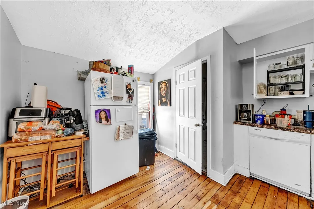 Kitchen featuring open shelves, light wood-type flooring, white appliances, baseboards, and a textured ceiling