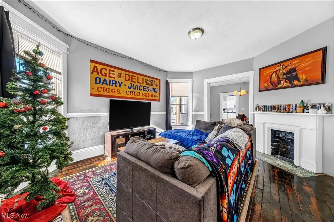 Living area featuring wood-type flooring, a fireplace with flush hearth, and wainscoting