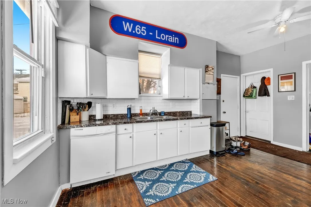 Kitchen with dark wood finished floors, a sink, tasteful backsplash, and dishwasher