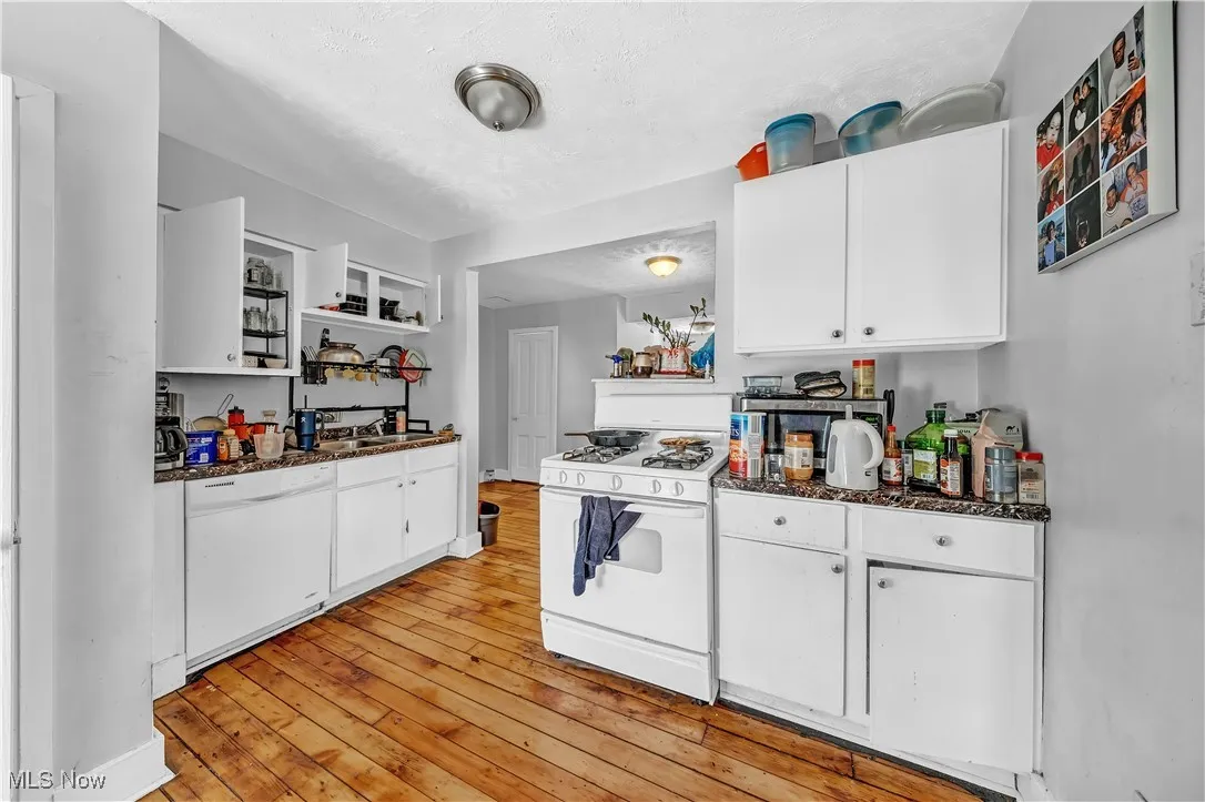Kitchen featuring white cabinetry, light wood-style flooring, open shelves, and white appliances