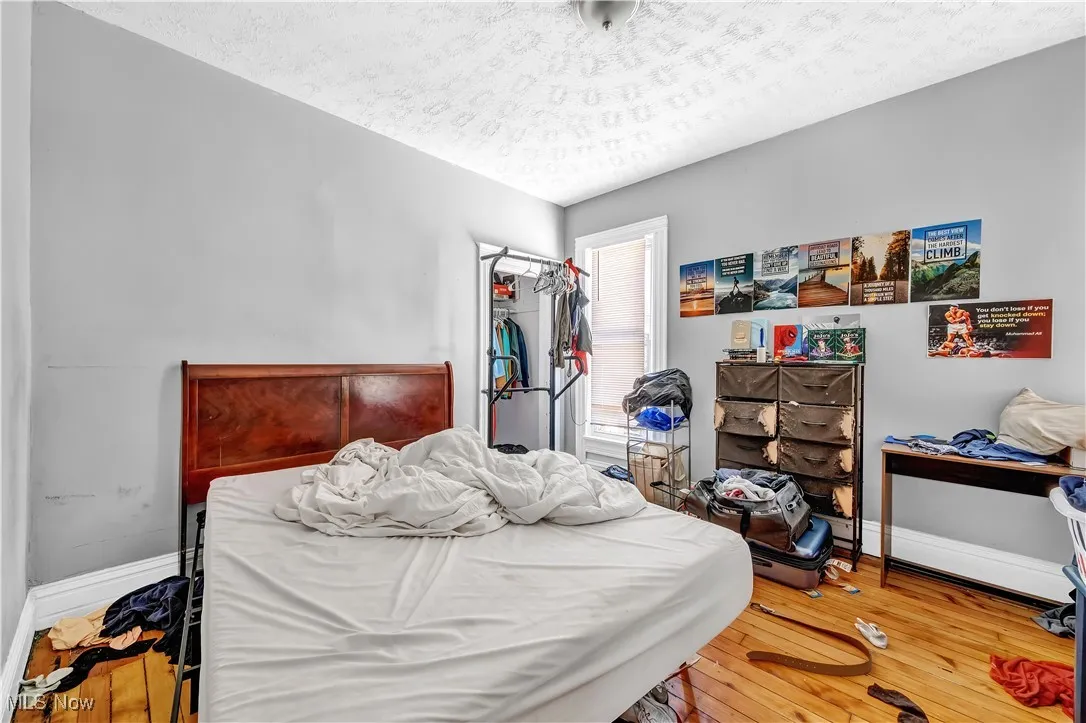 Bedroom with wood-type flooring, a closet, baseboards, and a textured ceiling