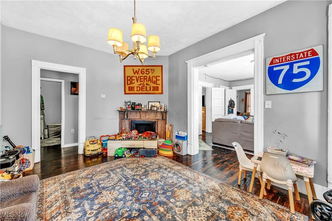 Game room with a notable chandelier, baseboards, a fireplace, and wood finished floors