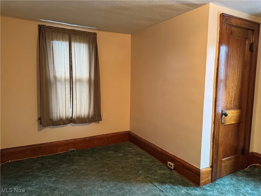 Carpeted spare room featuring baseboards and a textured ceiling