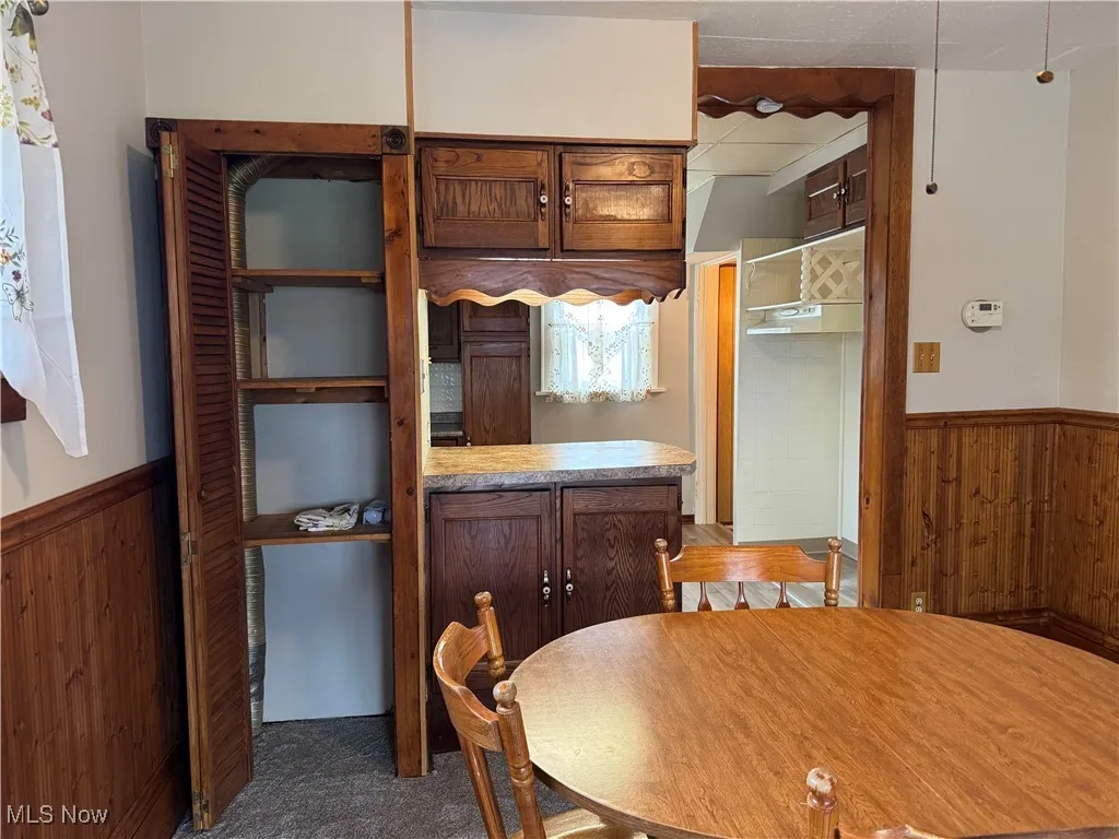 Unfurnished dining area with carpet, wooden walls, and wainscoting