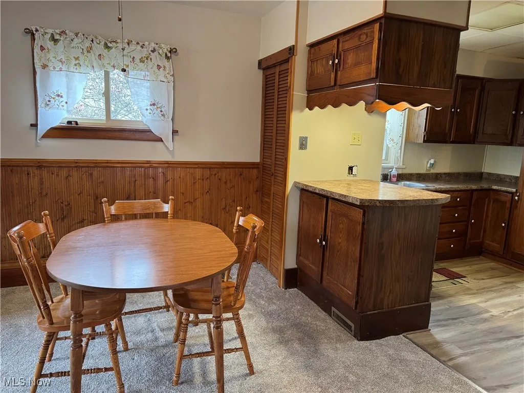 Dining room featuring light wood-style flooring, visible vents, wooden walls, and wainscoting