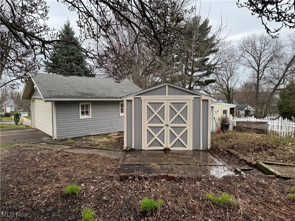 View of shed with driveway, fence, and a garage