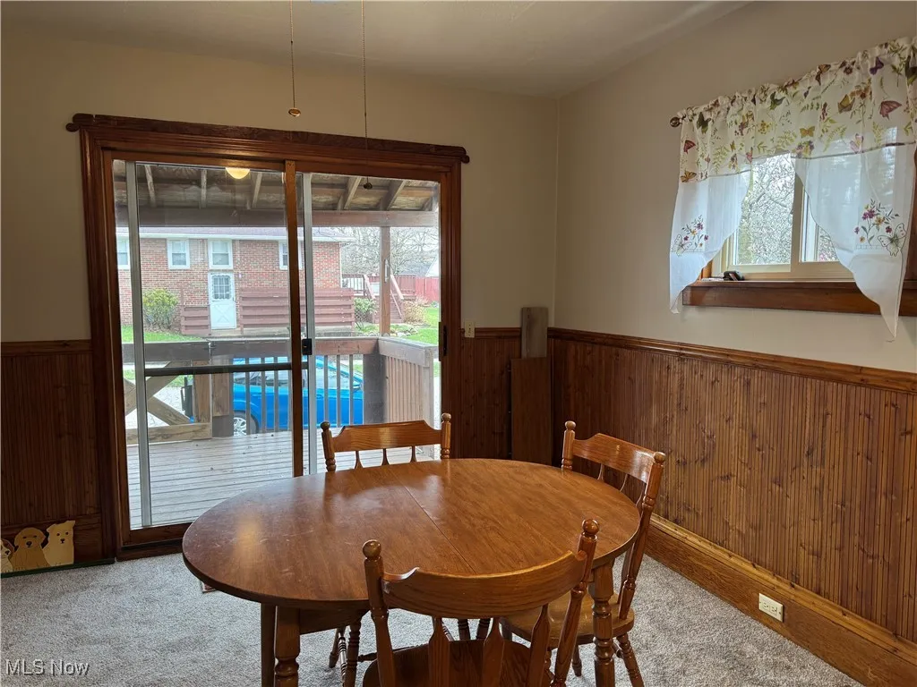 Carpeted dining space with wainscoting and wooden walls