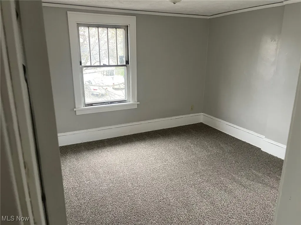Spare room featuring a textured ceiling, baseboards, and dark colored carpet