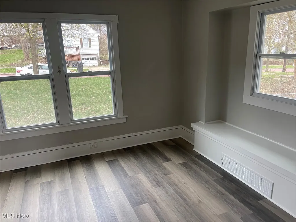 Spare room with a wealth of natural light and dark wood-style floors