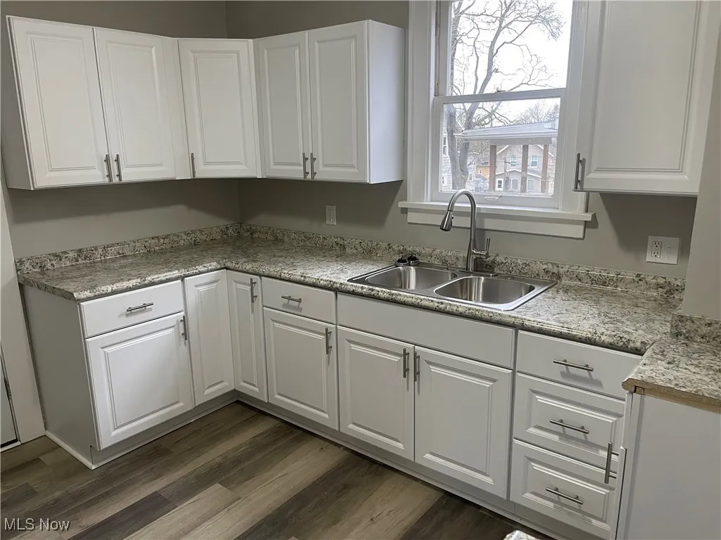 Kitchen with a sink, dark wood-style floors, and white cabinets