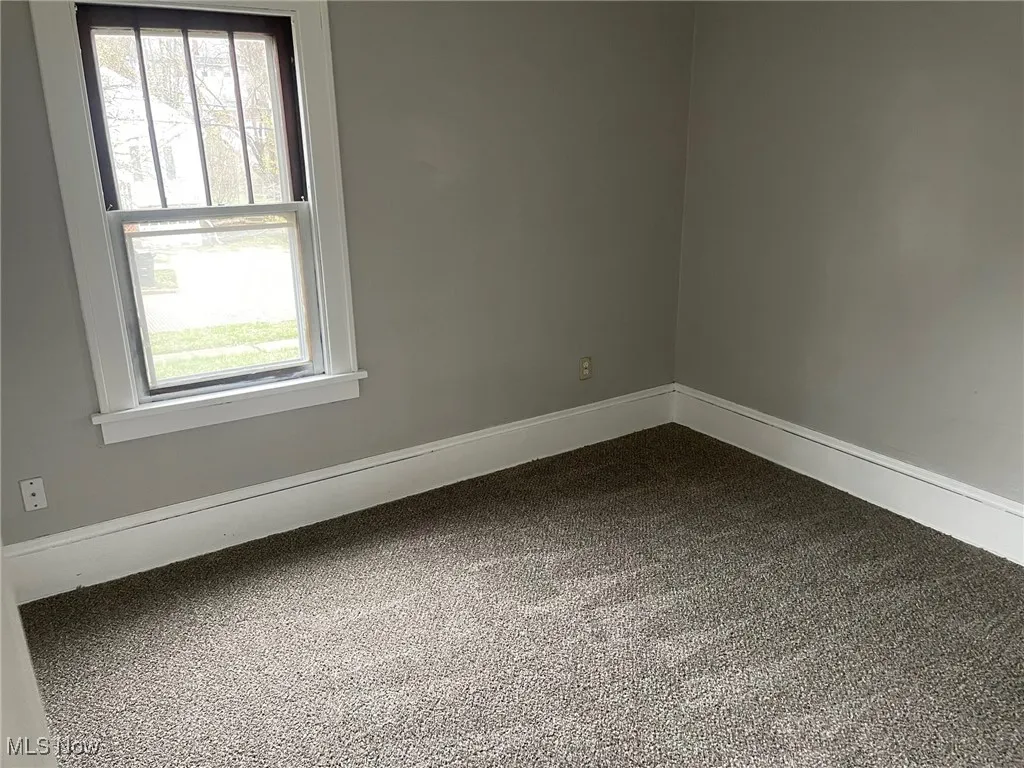 Empty room with dark carpet and baseboards