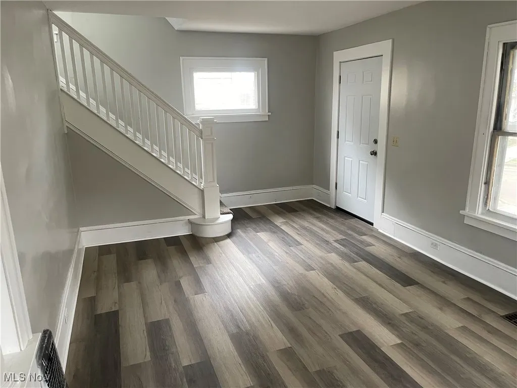 Foyer with wood finished floors, baseboards, and stairway