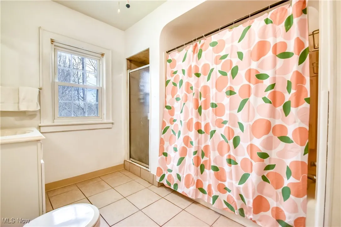 Full bath with tile patterned floors, vanity, baseboards, and a shower with shower curtain