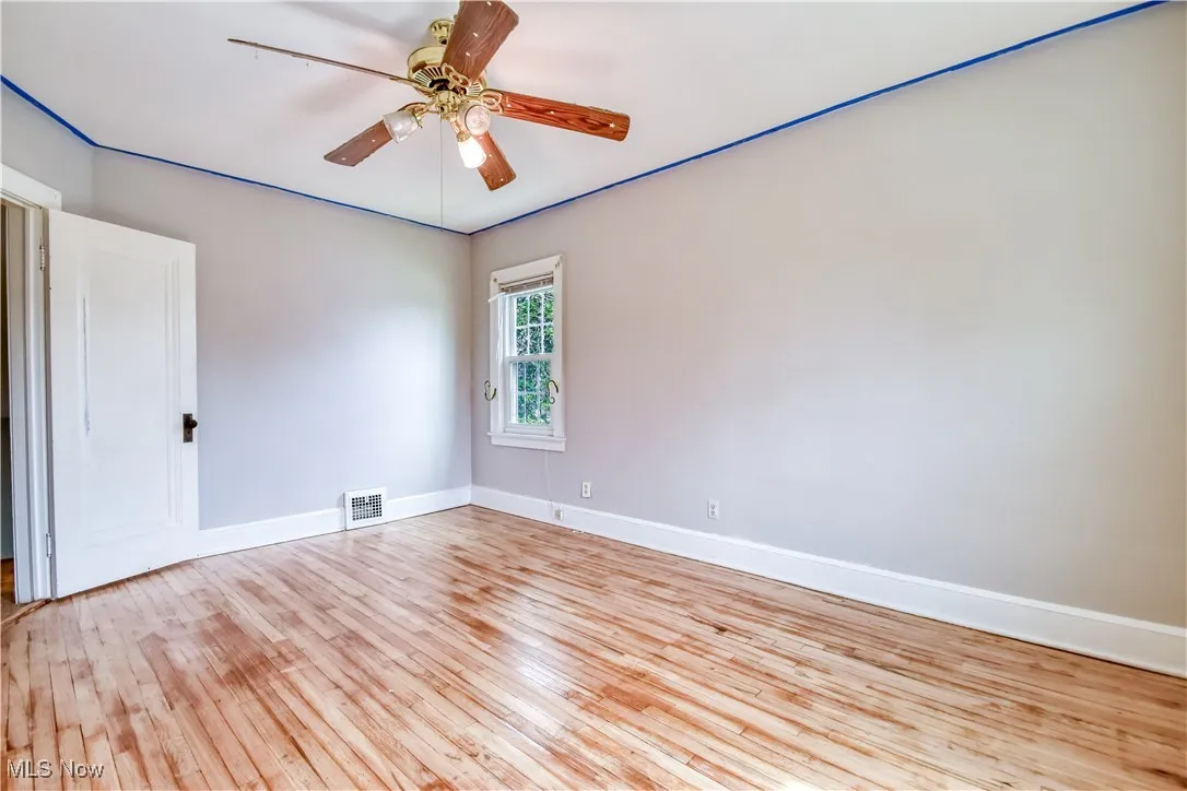 Empty room featuring baseboards, visible vents, a ceiling fan, and wood finished floors