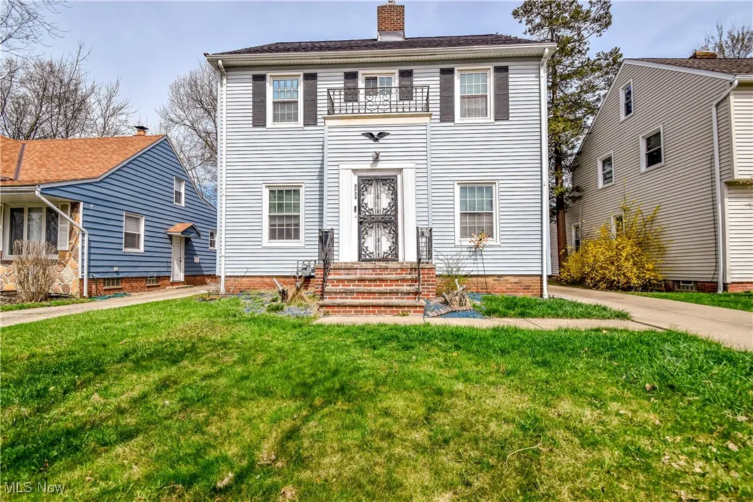 Colonial house featuring a balcony, a front yard, entry steps, and a chimney
