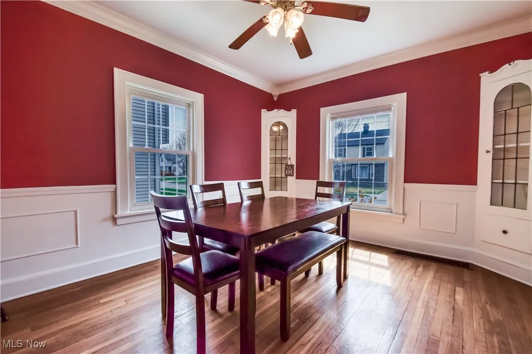 Dining space featuring ceiling fan, ornamental molding, wainscoting, and wood-type flooring