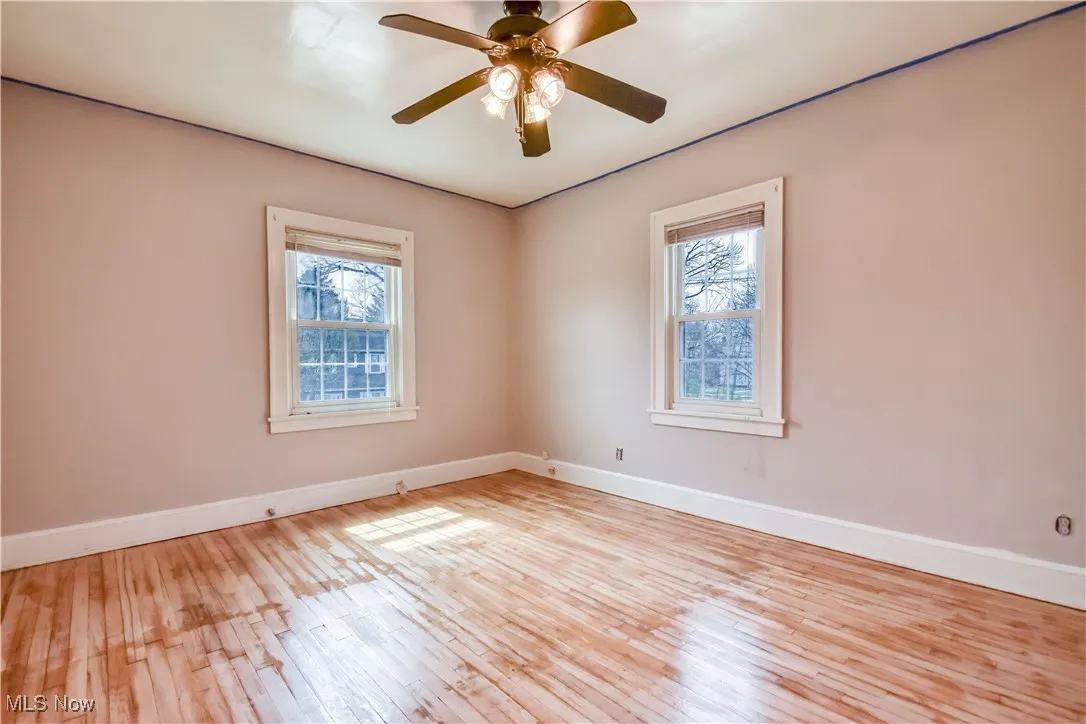 Unfurnished room with baseboards, ceiling fan, and wood-type flooring
