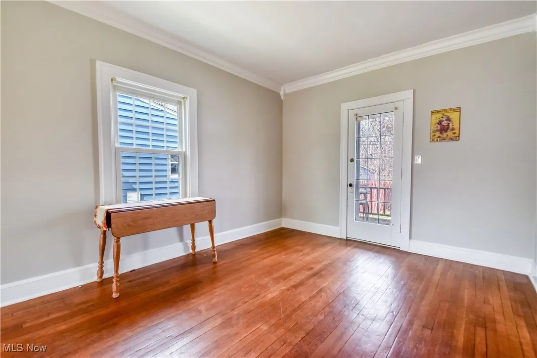 Unfurnished room featuring baseboards, crown molding, and wood-type flooring