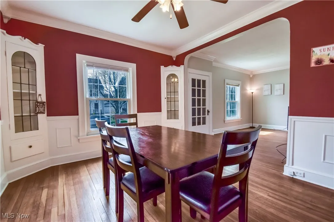 Dining space featuring a wainscoted wall, ceiling fan, ornamental molding, and hardwood / wood-style floors