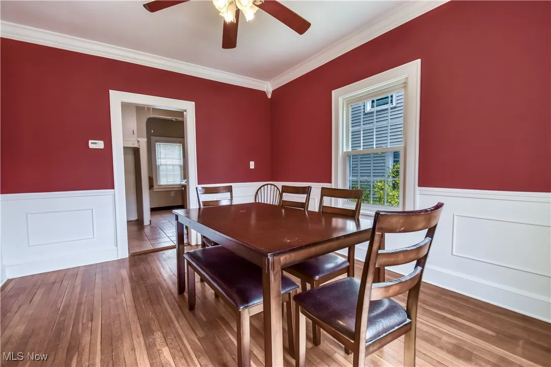 Dining room featuring a wainscoted wall, a ceiling fan, and wood-type flooring