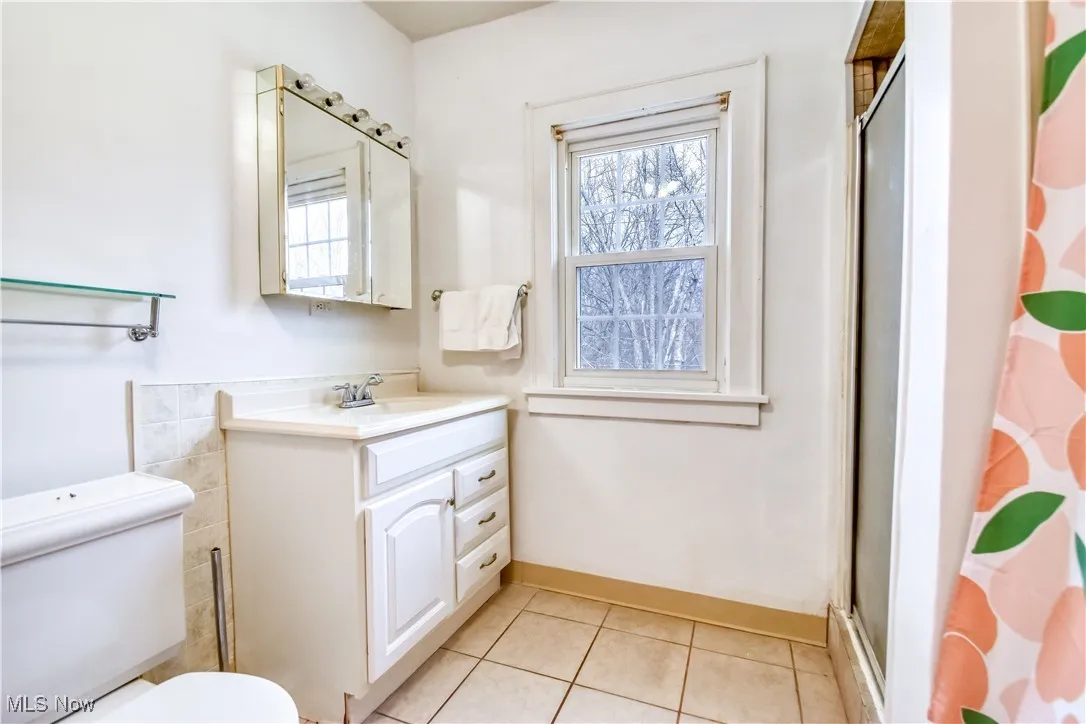 Bathroom featuring vanity, toilet, baseboards, tile patterned floors, and an enclosed shower