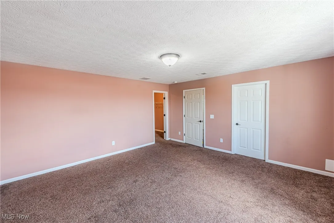 Carpeted spare room with baseboards and a textured ceiling