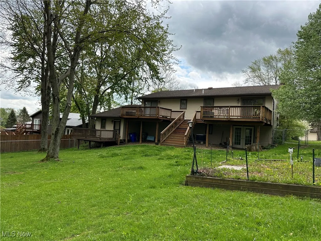 Back of property with fence, a wooden deck, a vegetable garden, and french doors