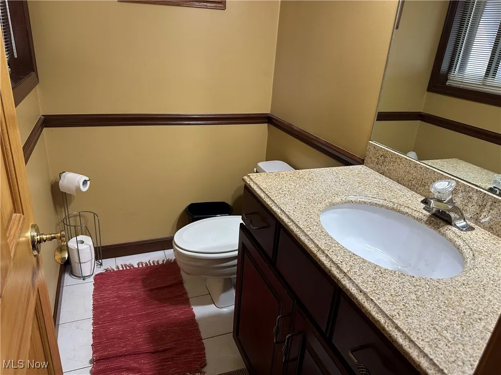 Bathroom featuring tile patterned floors, toilet, baseboards, and vanity