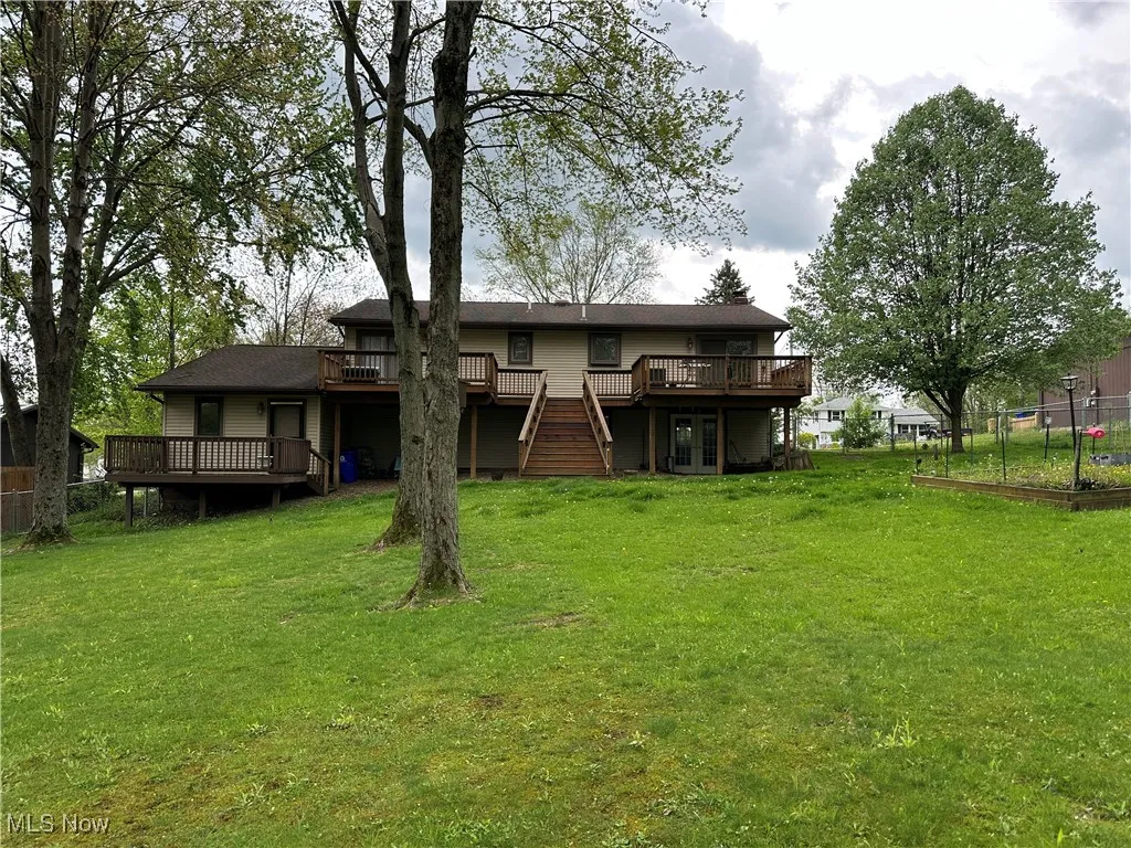 Back of house featuring a lawn, fence, a deck, and stairway