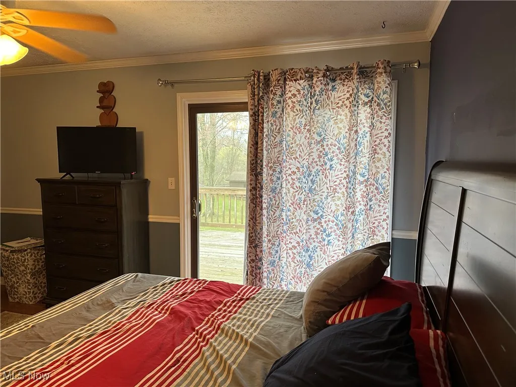 Bedroom featuring access to exterior, a ceiling fan, ornamental molding, and a textured ceiling