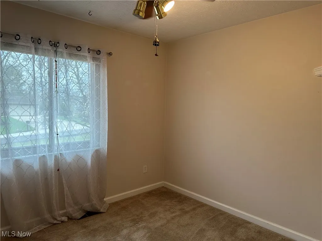 Empty room featuring baseboards, carpet flooring, and a textured ceiling