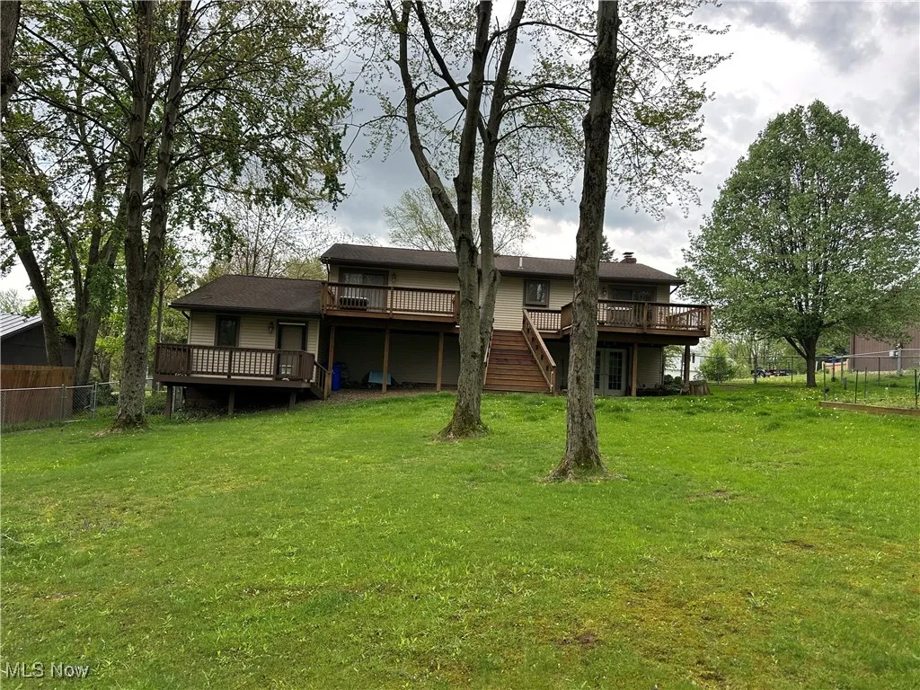 Back of house featuring fence, a yard, and a deck