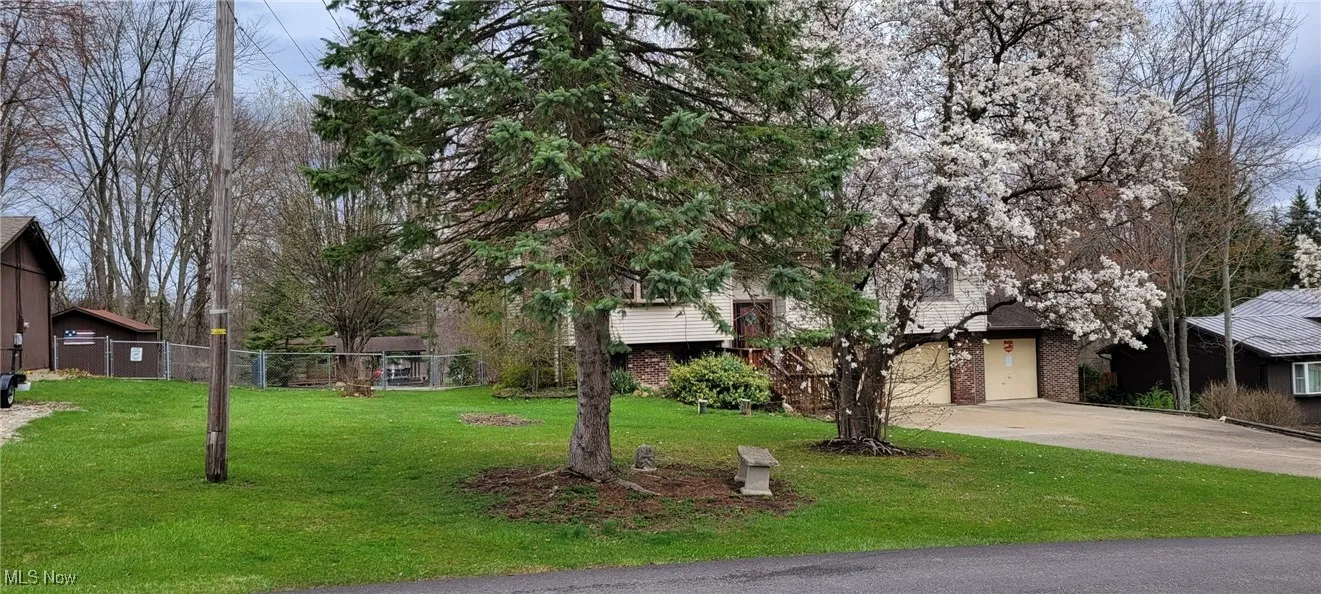 View of front of house featuring fence, a garage, concrete driveway, a front yard, and brick siding