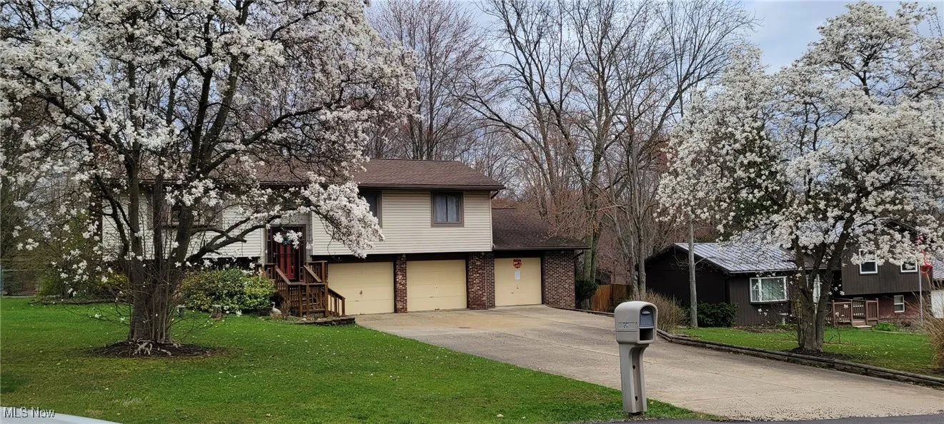 Split level home with a front yard, brick siding, concrete driveway, and a garage