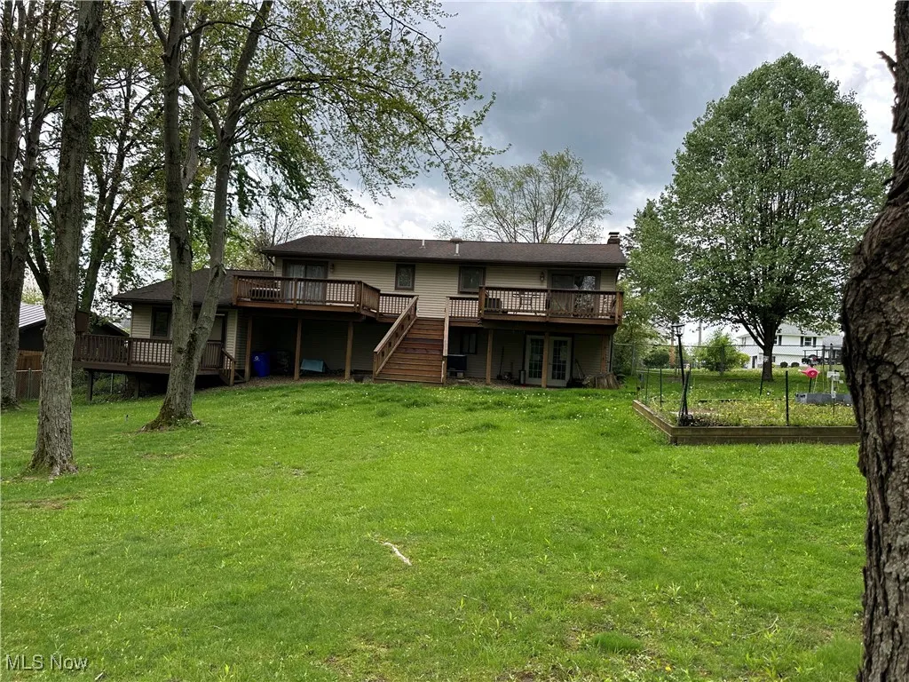 Back of property featuring a lawn, a wooden deck, french doors, and a chimney