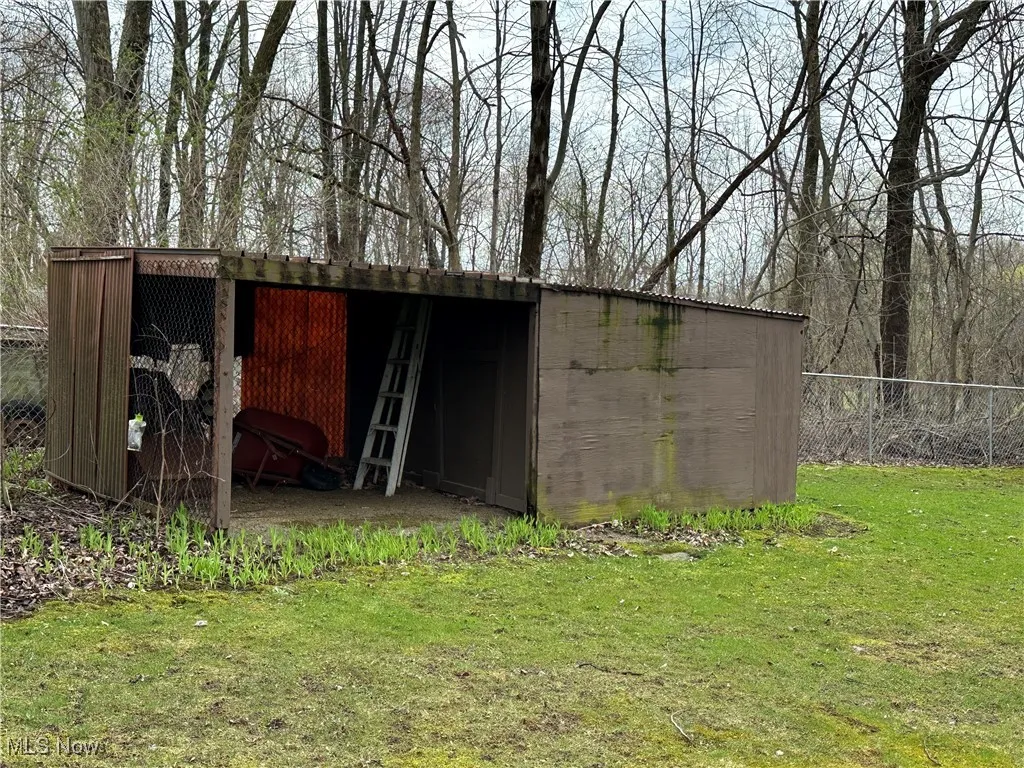 View of pole building with fence and a yard