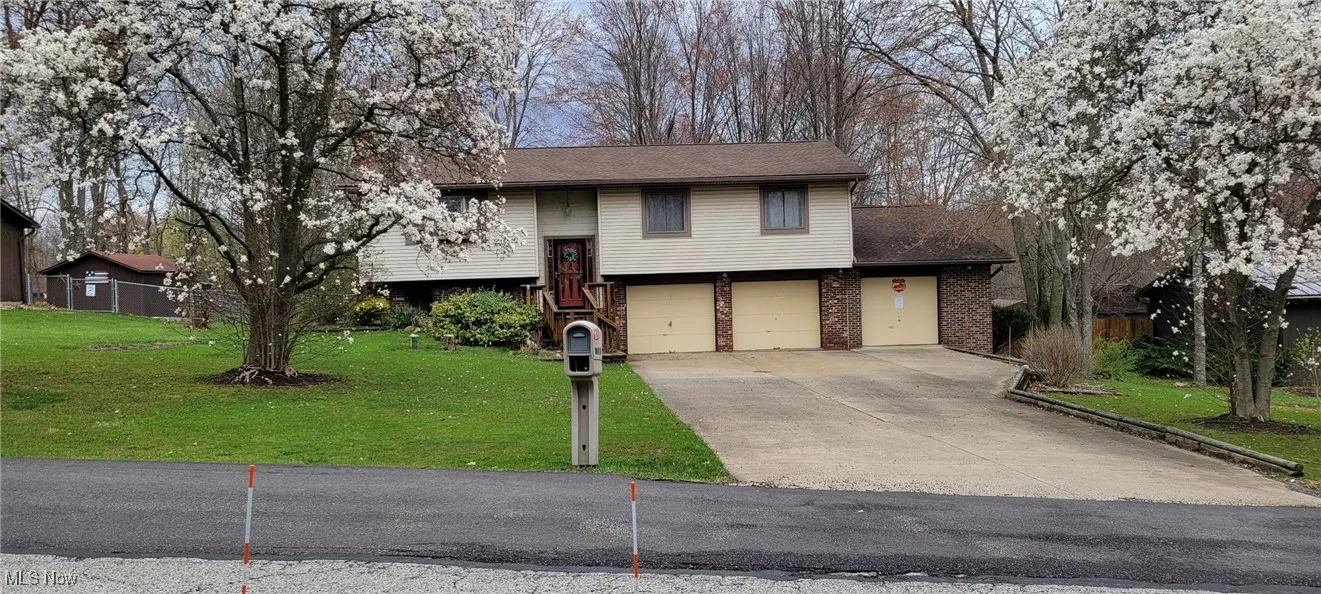 Bi-level home featuring a front yard, a garage, brick siding, and concrete driveway