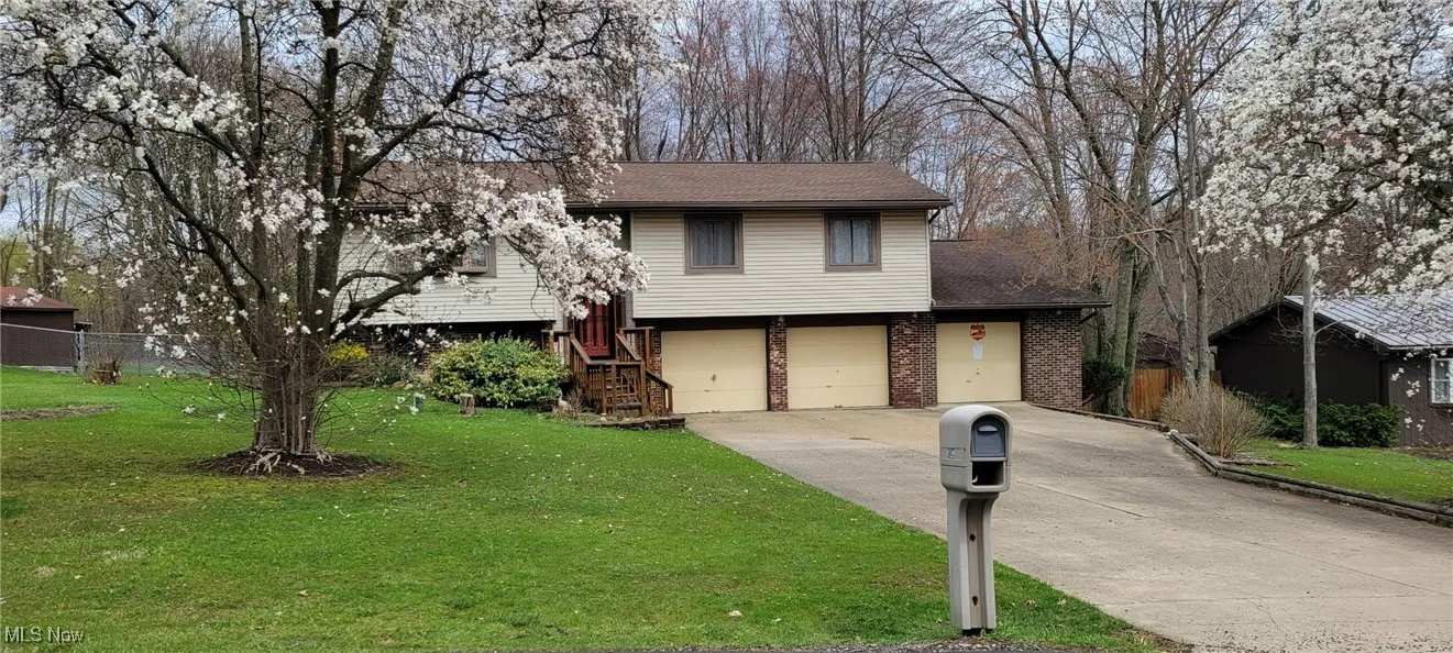 View of front facade with a front yard, concrete driveway, fence, brick siding, and a garage