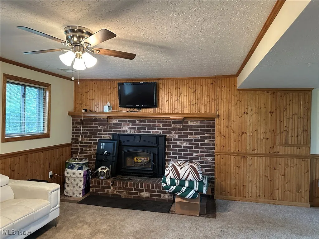 Living area featuring carpet floors, a textured ceiling, and ceiling fan