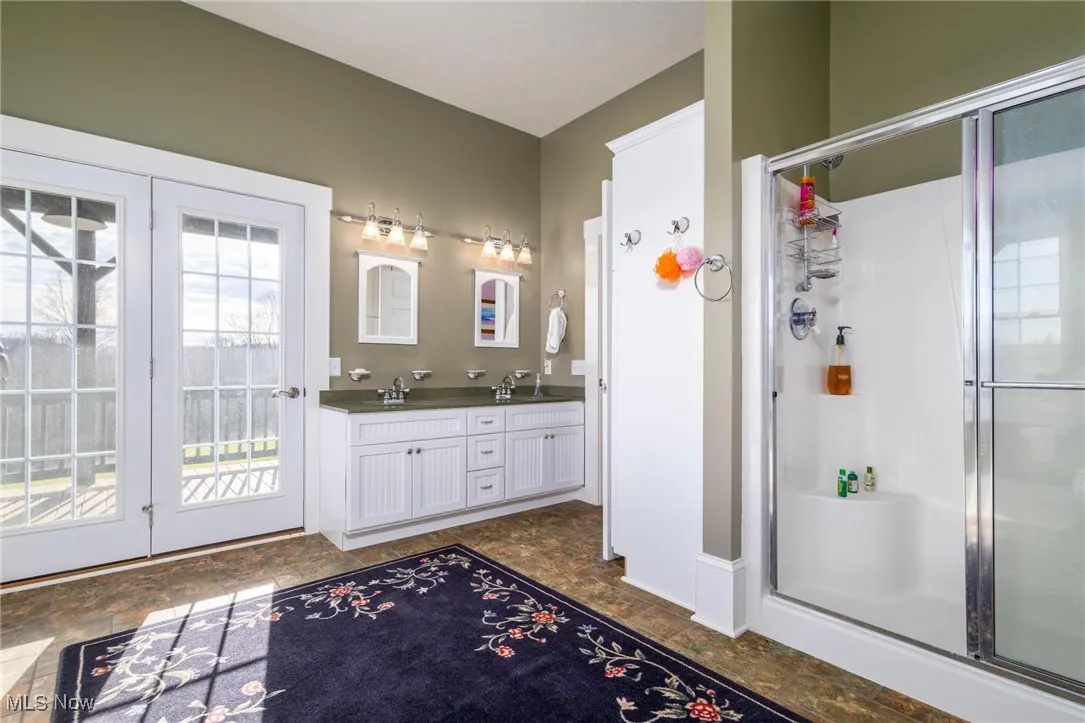Bathroom featuring dual vanity, a shower with shower door, tile floors, and plenty of natural light