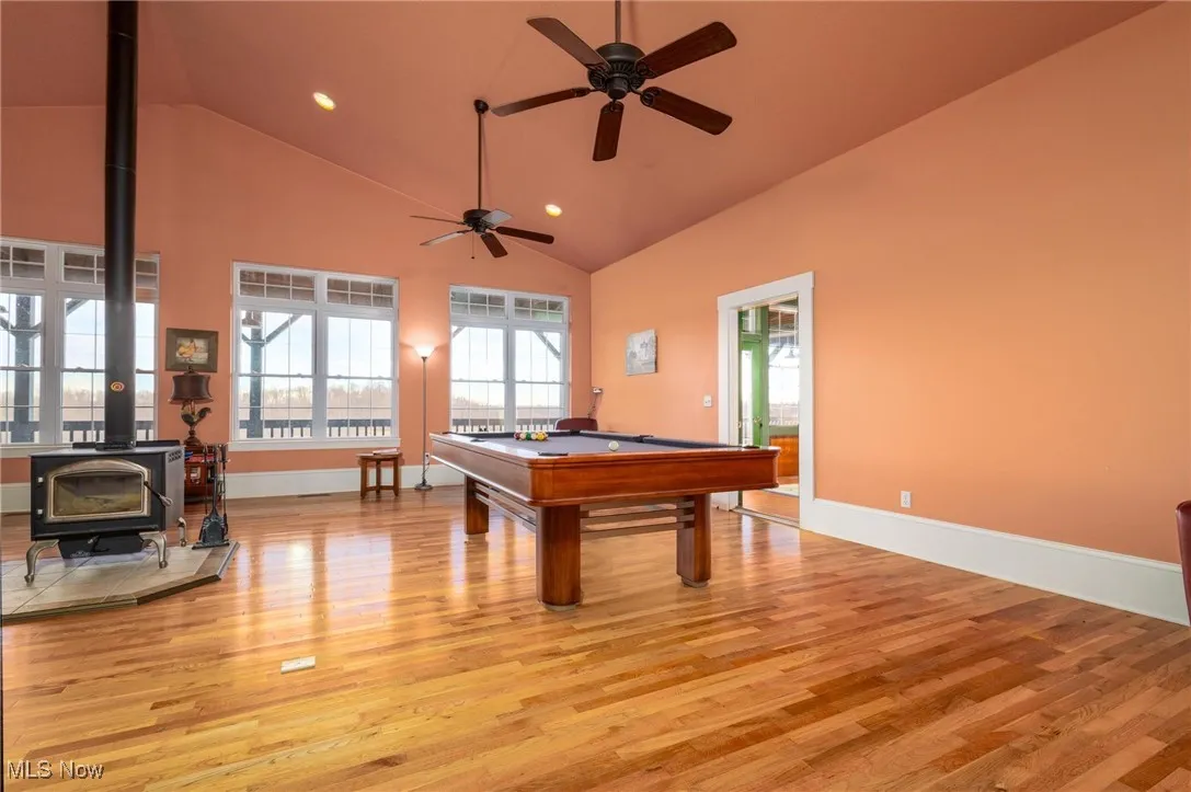 Recreation room featuring billiards, a wood stove, light wood-type flooring, and ceiling fan