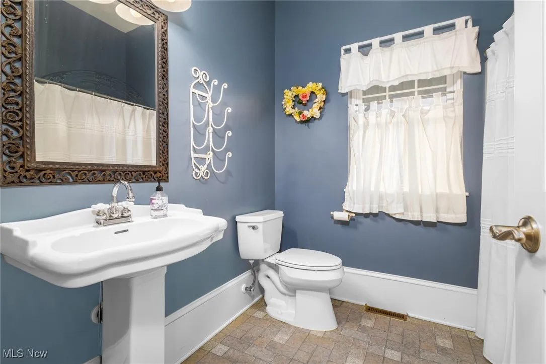 Bathroom with toilet, tile floors, and sink